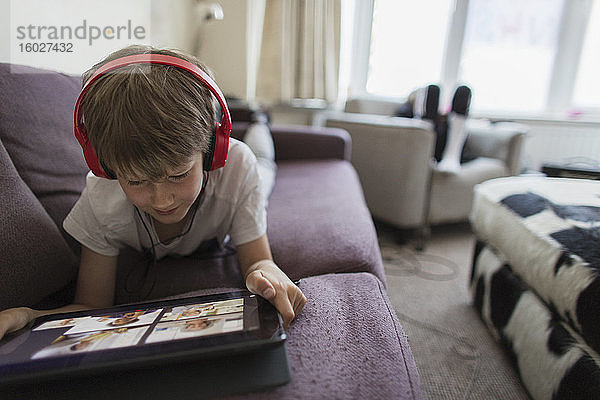 Junge mit Kopfhörern und digitalem Tablet Heimunterricht auf dem Sofa