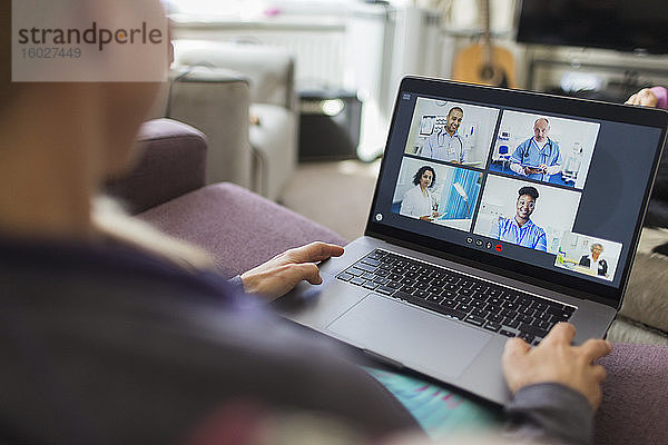 Frau mit Laptop im Video-Chat mit Ärzten vom Sofa aus