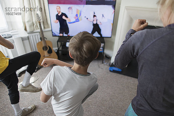 Mutter und Söhne üben online am Fernseher im Wohnzimmer
