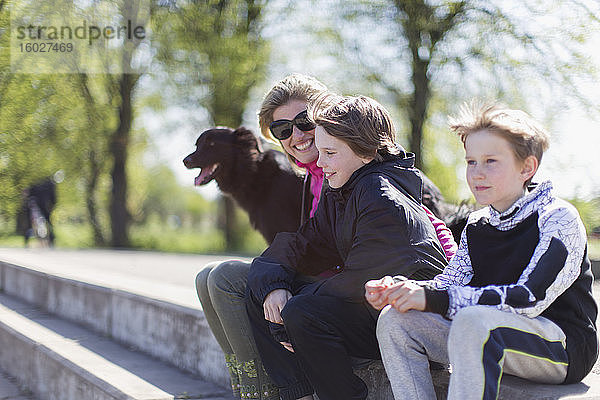 Glückliche Mutter und Söhne mit Hund im sonnigen Park