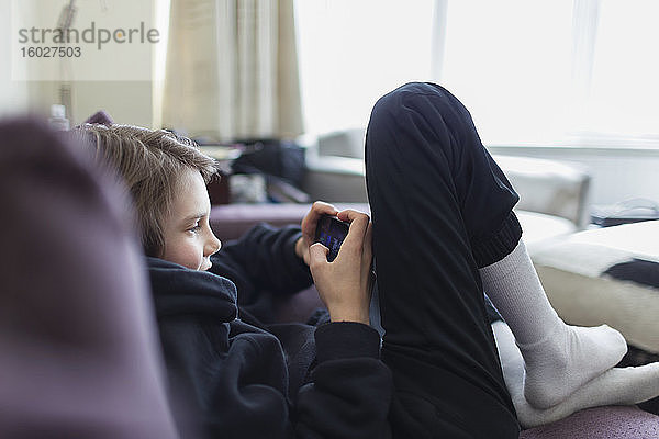 Junge spielt Videospiel mit Smartphone auf dem Sofa