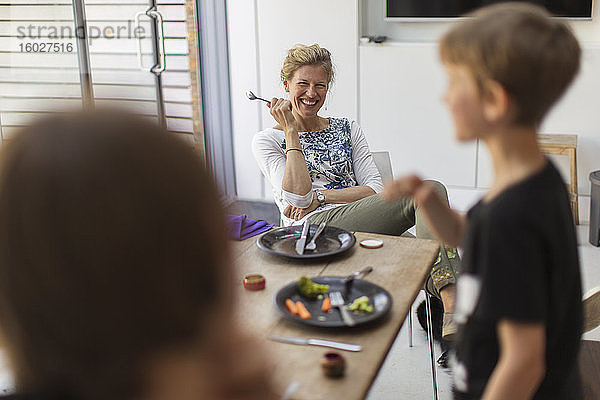 Glückliche Mutter und Söhne essen zu Hause zu Mittag