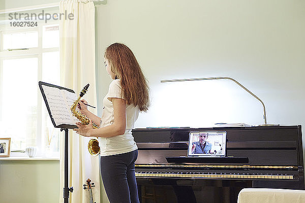 Mädchen nimmt zu Hause Online-Saxophonunterricht