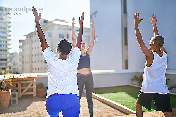 Freunde praktizieren Yoga auf einem sonnigen städtischen Dach