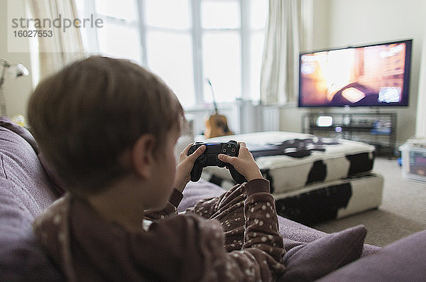 Junge spielt Videospiel auf Wohnzimmer-Sofa