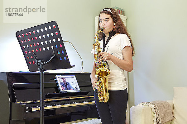 Mädchen nimmt zu Hause Online-Saxophonunterricht