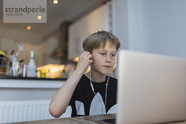 Junge mit Kopfhörern beim Heimunterricht am Laptop