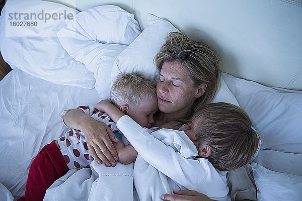 Mutter mit im Bett schlafenden Söhnen