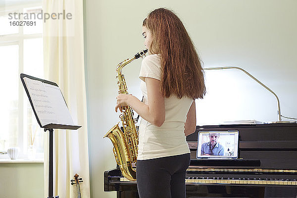 Mädchen nimmt zu Hause Online-Saxophonunterricht