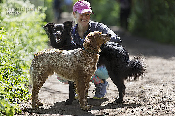 Glückliche Frau mit Hunden auf Wanderweg