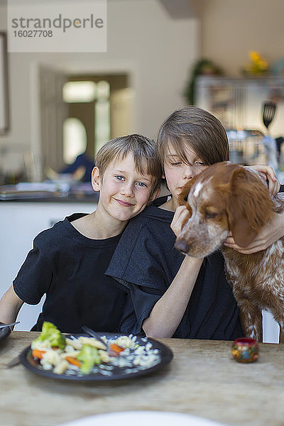 Porträt Brüder mit Hund beim Essen am Esstisch