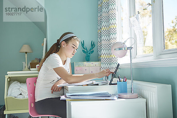 Fokussierter Heimunterricht für Mädchen am Schreibtisch im Schlafzimmer