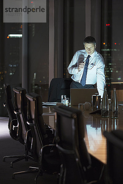Geschäftsmann arbeitet nachts am Laptop im Konferenzraum