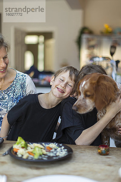 Glückliche Familie mit Hund beim Mittagessen am Esstisch