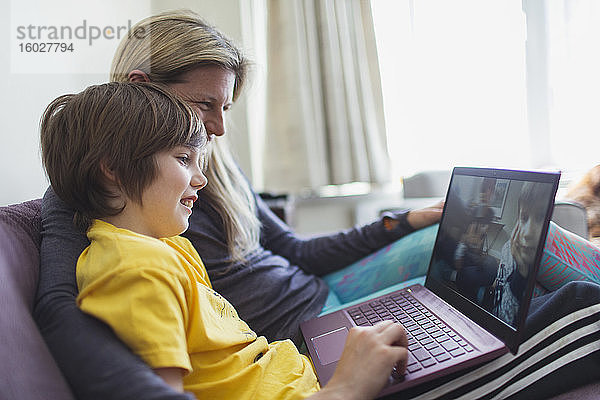 Mutter und Sohn benutzen Laptop auf dem Sofa