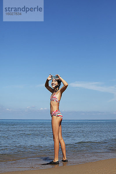 Lächelndes Mädchen mit Brille und Schwimmflossen am Strand