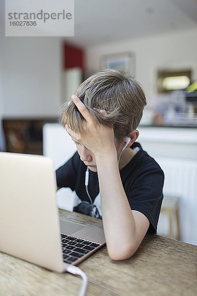 Junge mit Kopfhörern beim Heimunterricht am Laptop