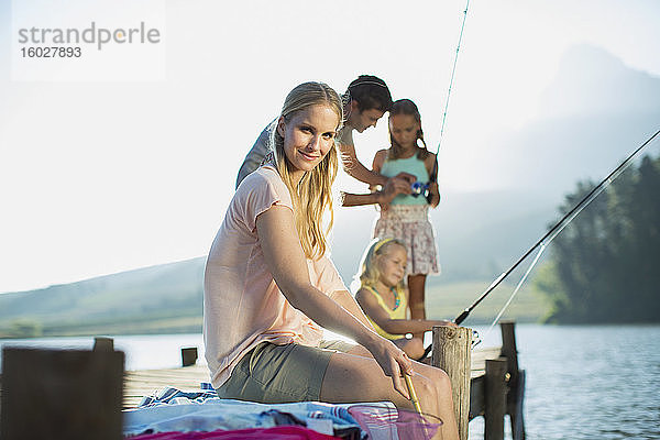 Lächelnde Frau mit Familie beim Angeln am Dock über dem See