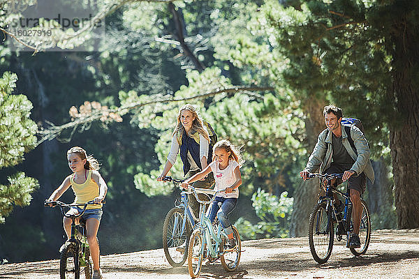 Lächelndes Familienradfahren im Wald