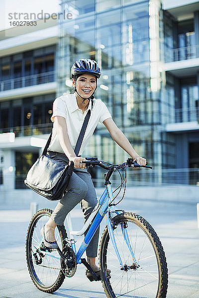 Lächelnde Frau mit dem Fahrrad auf dem städtischen Bürgersteig