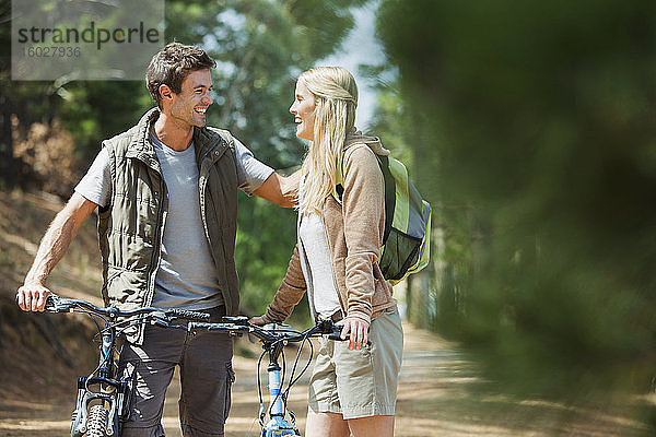 Lächelndes Paar mit Mountainbikes im Wald