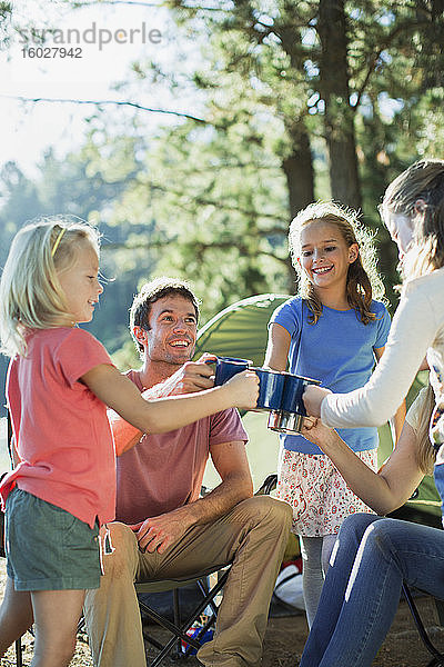 Familie röstet Becher auf einem Campingplatz im Wald