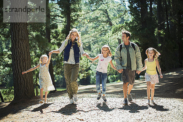 Lächelnde Familie beim Händchenhalten und Waldspaziergang