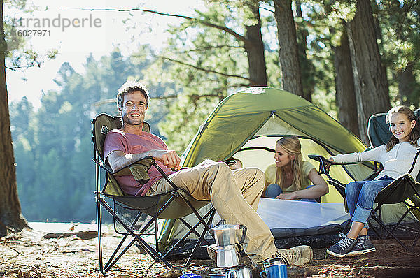 Lächelnde Familie entspannt sich auf einem Campingplatz im Wald