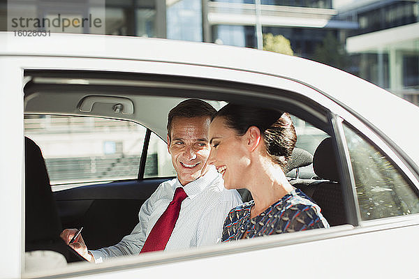 Geschäftsmann und Geschäftsfrau unterhalten sich auf dem Rücksitz eines Autos