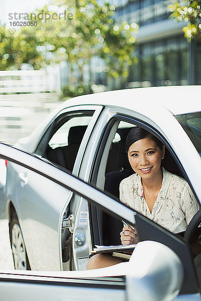 Lächelnde Geschäftsfrau sitzt im Auto