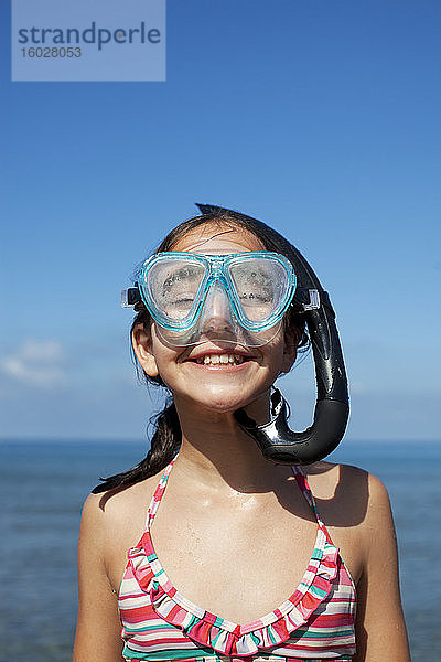 Glückliches Mädchen mit Schnorchel und Schutzbrille am Strand