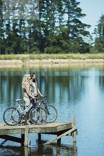 Paar mit Fahrrädern auf dem Dock mit Blick auf den See