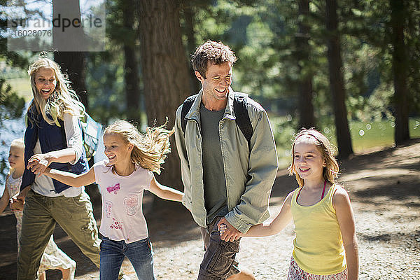 Lächelnde Familie beim Händchenhalten und Waldspaziergang