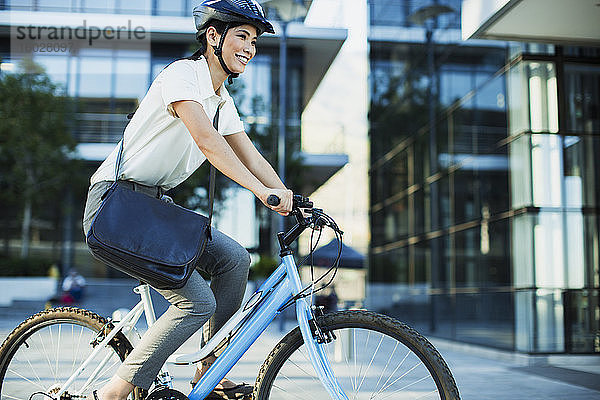 Geschäftsfrau beim Radfahren vor einem städtischen Gebäude