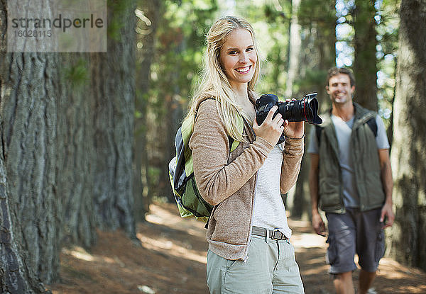 Lächelnde Frau mit Digitalkamera im Wald