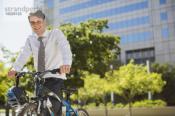 Lächelnder Geschäftsmann mit Fahrrad im Freien