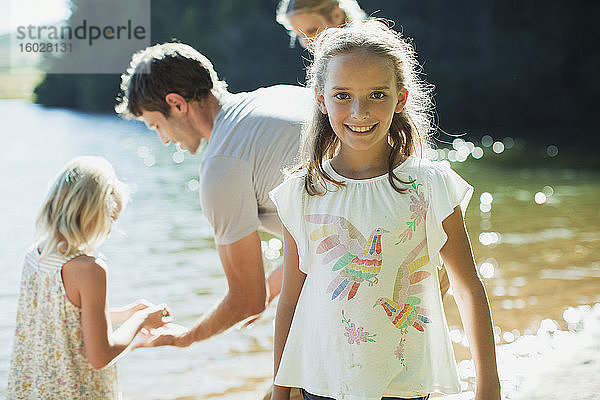 Lächelndes Mädchen mit Familie am Seeufer