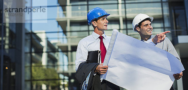 Architekten mit Blaupausen vor städtischen Gebäuden