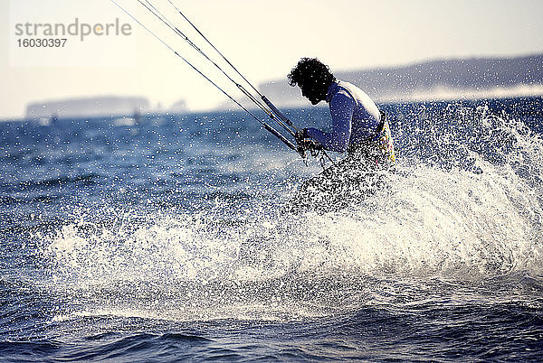 Seitenansicht eines Mannes beim Kitesurfen auf dem Ozean.