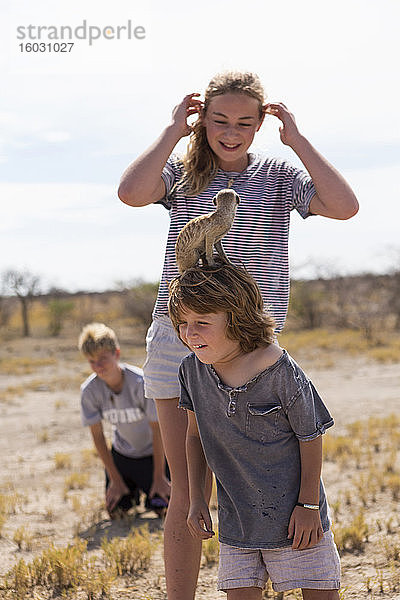 5 Jahre alter Junge mit Erdmännchen auf dem Kopf  Kalahari-Wüste  Makgadikgadi-Salzpfannen  Botswana