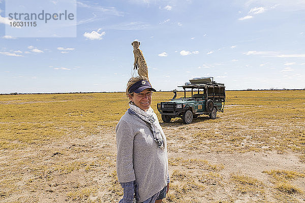 erwachsene Frau mit Erdmännchen auf dem Kopf  Kalahari-Wüste  Makgadikgadi-Salzpfannen  Botswana