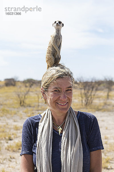 erwachsene Frau mit Erdmännchen auf dem Kopf  Kalahari-Wüste  Makgadikgadi-Salzpfannen  Botswana