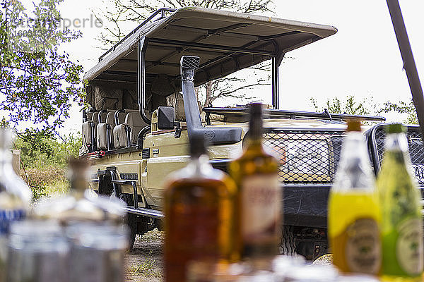 Safarifahrzeug geparkt  Picknicktisch mit Flaschen und Lebensmitteln gedeckt.