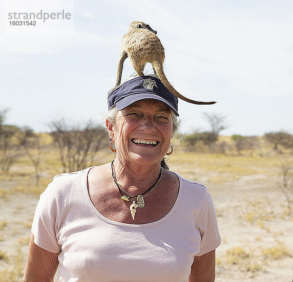 lächelnde ältere Frau mit Erdmännchen auf dem Kopf  Kalahari-Wüste  Makgadikgadi-Salzpfannen  Botswana