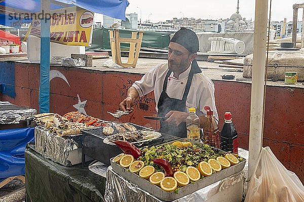 Mann verkauft gegrillte Fische an einem Verkaufsstand  Fischmarkt  Karaköy  Istanbul  Türkei  Asien