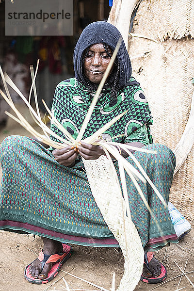 Ältere Frau arbeitet mit Stroh im Dorf Melabday  Asso Bhole  Dallol  Danakil Depression  Afar Region  Äthiopien  Afrika
