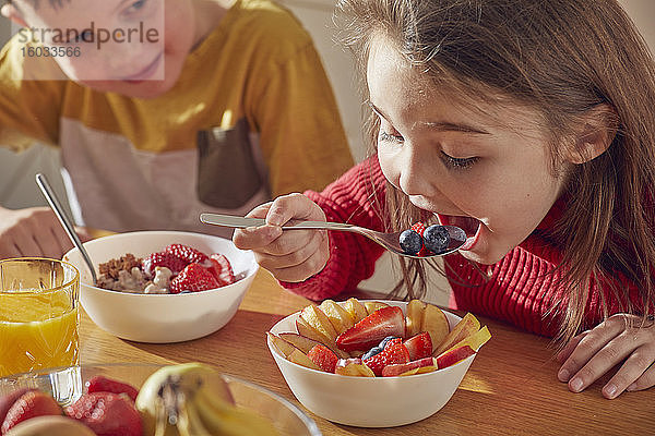 Junge und Mädchen sitzen am Küchentisch und essen Frühstück.