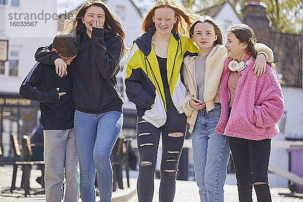 Gruppe von Mädchen und Jungen im Teenageralter  die Seite an Seite im Freien spazieren gehen.