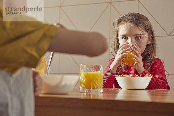 Junge und Mädchen sitzen am Küchentisch und essen Frühstück.