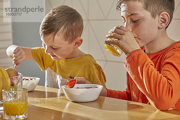 Zwei Jungen sitzen am Küchentisch und frühstücken.